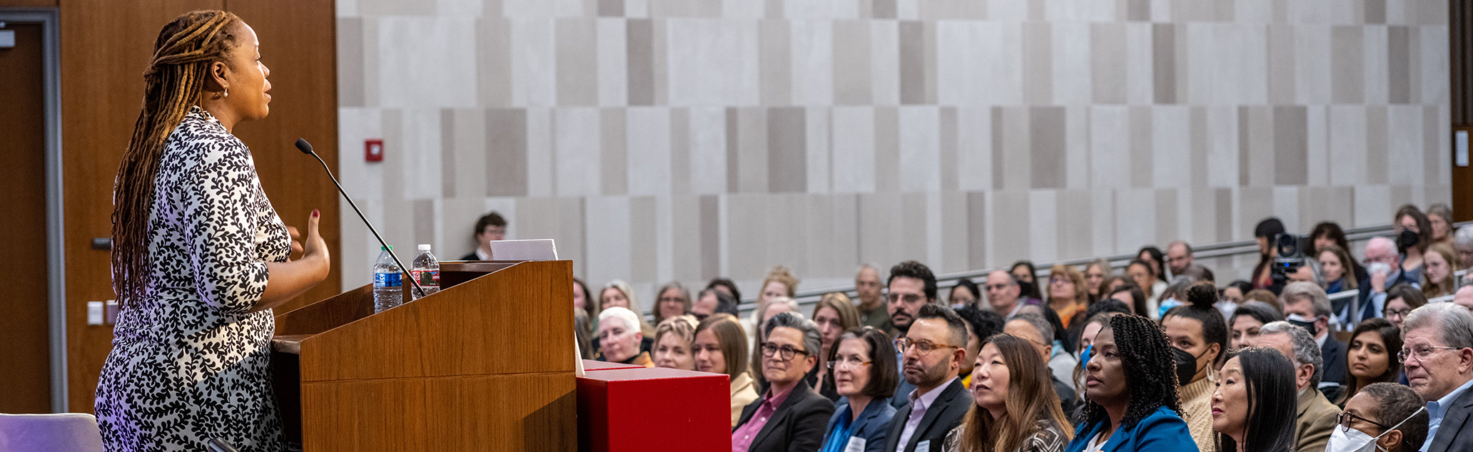 African-american woman stands at a podium giving a lecture.